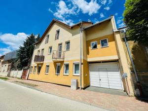 a yellow house with a garage on a street at Gold Apartman in Nagykanizsa