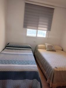 two beds in a small bedroom with a window at Apartment Cala Dor in El Campello