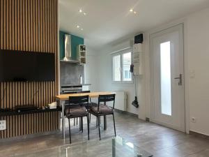 a kitchen with a table and chairs and a television at maison proche du Groupama Stadium in Décines-Charpieu