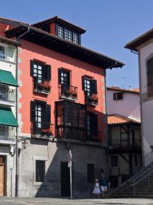 a red building with balconies on a street at Hotel Palacio Oxangoiti in Lekeitio
