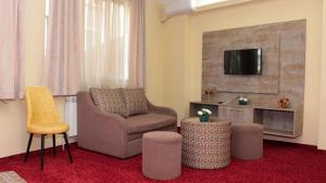 ein Wohnzimmer mit einem Stuhl und einem TV in der Unterkunft Хотел Хилез Hotel Hilez in Trjawna
