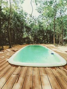 a swimming pool on a wooden deck with trees at Zil-Kaab Hidden Glamping Village in Tulum