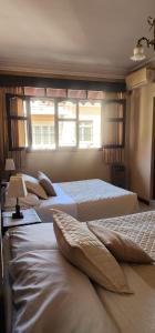 three beds in a room with two windows at Hotel Carmen in Tarija