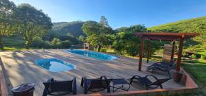 a wooden deck with chairs and a swimming pool at Chalé Pavão Recanto Buscapé SFX in São Francisco Xavier