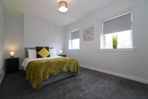 a white bedroom with a bed and two windows at Signature - Huntley House in Glasgow