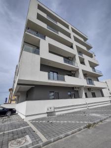 a tall white building with a car parked in front of it at Apartament Sunshine in Năvodari +4 photos