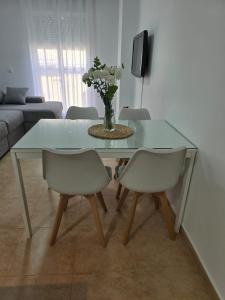 ein Glastisch mit zwei Stühlen und einer Vase mit Blumen in der Unterkunft Apartamento Calle Calvario in Rota