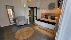 Mykonos Double Luxury Mini Suites - Adults only في أنو ميرا: غرفة نوم بسرير وكرسي وطاولة