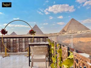 Comfort Sphinx Inn في القاهرة: بلكونه مع طاوله وكراسي والاهرامات