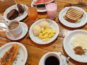 a wooden table with plates of breakfast foods and drinks at Chalé Faisão Recanto Buscapé SFX in São Francisco Xavier