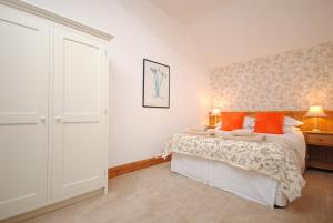a bedroom with a bed with orange pillows at The Byre, Heritage Escapes, Field House Farm in Bempton
