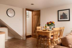 a dining room with a table and chairs and a clock at The Byre, Heritage Escapes, Field House Farm in Bempton +6 photos