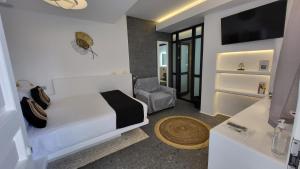 Mykonos Double Luxury Mini Suites - Adults only في أنو ميرا: غرفة نوم بسرير وكرسي في غرفة