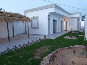ein kleines weißes Haus mit einem Rasenhof in der Unterkunft Villa LELLA HADHERYA in Taguermess