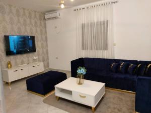 ein Wohnzimmer mit einem blauen Sofa und einem Fernseher in der Unterkunft Villa LELLA HADHERYA in Taguermess
