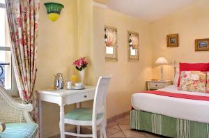 a room with a bed, chair, table and lamp at Hôtel La Grande Bastide in Saint Paul de Vence