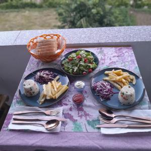 einen Tisch mit Teller mit Speisen und einem Korb mit Salat in der Unterkunft Guest House Artjon in Fierzë