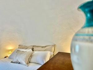 a bed with white pillows and a vase on a table at Trulli Duomo di Calce in Alberobello +37 photos