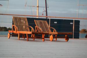 two wooden benches sitting next to a boat at Hausboot Kaddi`s SunDREAM - Huus & Meer in Fehmarn