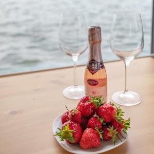 a plate of strawberries on a table with two wine glasses at Hausboot Kaddi`s SunDREAM - Huus & Meer in Fehmarn