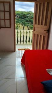 Zimmer mit einem roten Bett und einer Tür mit Aussicht in der Unterkunft Pousada & Camping Recanto dos Anjos Azuis in Paty do Alferes