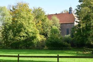 an old house with a fence in front of a field at Ferienwohnung Maria im alten Pastorat in Kevelaer +2 photos