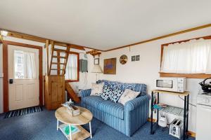 Dream Harbor Cottage في Surry: غرفة معيشة مع أريكة زرقاء وميكروويف