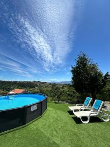 two chairs and a swimming pool on a lawn at Vila Teixeira in Amarante