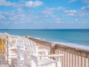 a row of white chairs on the beach at A Grande Green in Surf City