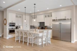 a kitchen with white cabinets and a stainless steel refrigerator at The Solace at Desert Color by Ember Stays in St. George