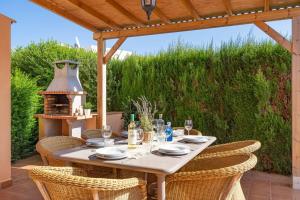 uma mesa com cadeiras sentadas sob uma pérgola de madeira em Villa Marcolis Playa em Cala Galdana