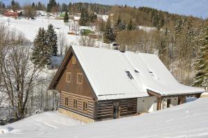 a wooden house with snow on the roof at Roubenka Pod hvězdami in Strážné