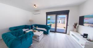 a living room with blue furniture and a view of the beach at Villa Elysian Blagaj in Blagaj