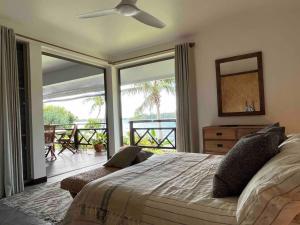 a bedroom with a bed with a view of a balcony at Blue Coral House, Luxury Waterfront in Maroe