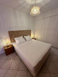 een slaapkamer met een groot wit bed en een kroonluchter bij Kavos Apartments in Patitiri