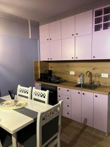 a kitchen with white cabinets and a table and a sink at Mirelas guesthouse in Pogradec