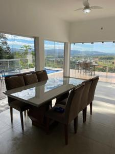 a dining room with a glass table and chairs at Casa Capitólio com Vista para Escarpas do Lago in Capitólio