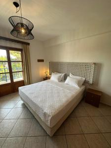 een slaapkamer met een groot wit bed en een lamp bij Kavos Apartments in Patitiri
