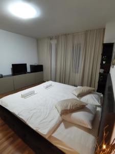 a bedroom with a large bed with white sheets and pillows at CC Accommodation in Popeşti-Leordeni