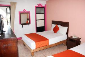 a hotel room with two beds and a mirror at Hotel Huautla de Oaxaca in Oaxaca City