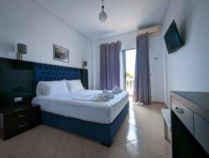 a bedroom with a large bed with a blue headboard at Hotel Fron in Sarandë