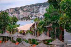 a group of tables with umbrellas in front of a building at Hotel Fron in Sarandë