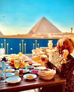 Uma mulher está sentada numa mesa com comida. em Comfort Sphinx Inn no Cairo