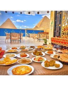 Comfort Sphinx Inn في القاهرة: طاولة مليئة بأطباق الطعام مع الأهرامات في الخلفية