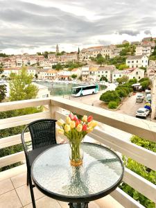 a glass table with a vase of flowers on a balcony at Apartman Zorka in Povlja