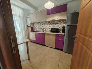 a kitchen with purple cabinets and a refrigerator at Apartments in Solid House Mamaia in Mamaia