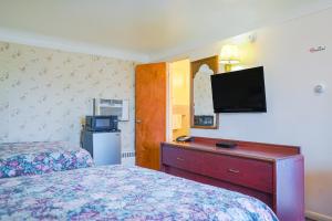 sypialnia z dwoma łóżkami i telewizorem na ścianie w obiekcie Bay Motel By OYO Bay City w mieście Bay City