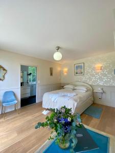 Le Rheuにあるシャトー ダピン レンヌのベッドと花が飾られたテーブルのある寝室
