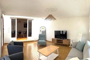 a living room with a couch and a tv at Maison historique familiale 300m de la mer Sword Beach in Ouistreham +2 photos