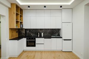 a kitchen with white cabinets and black appliances at Oasis apartment in Chişinău